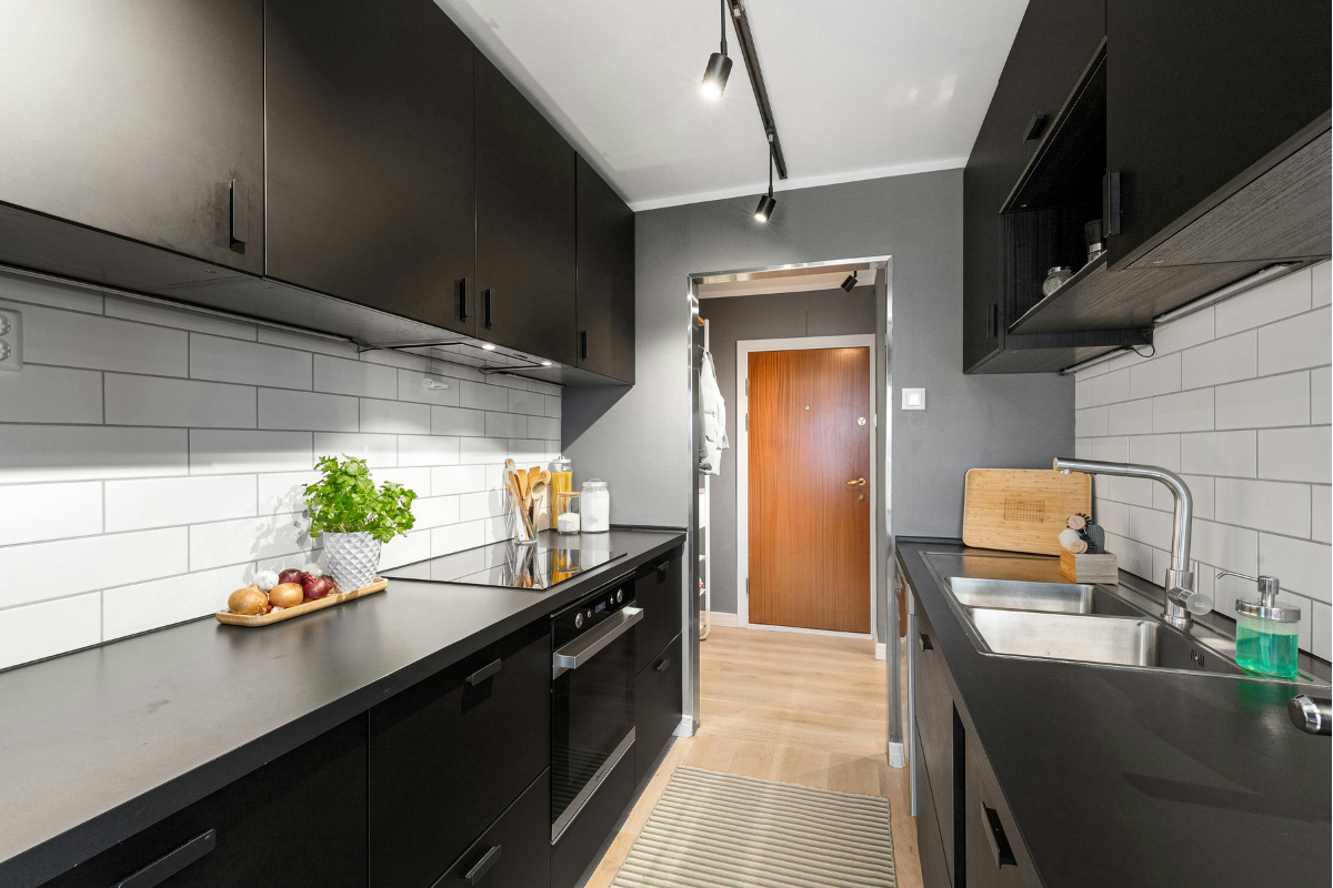 Space-efficient parallel kitchen with laminate finish, overhead cabinets, and utility area