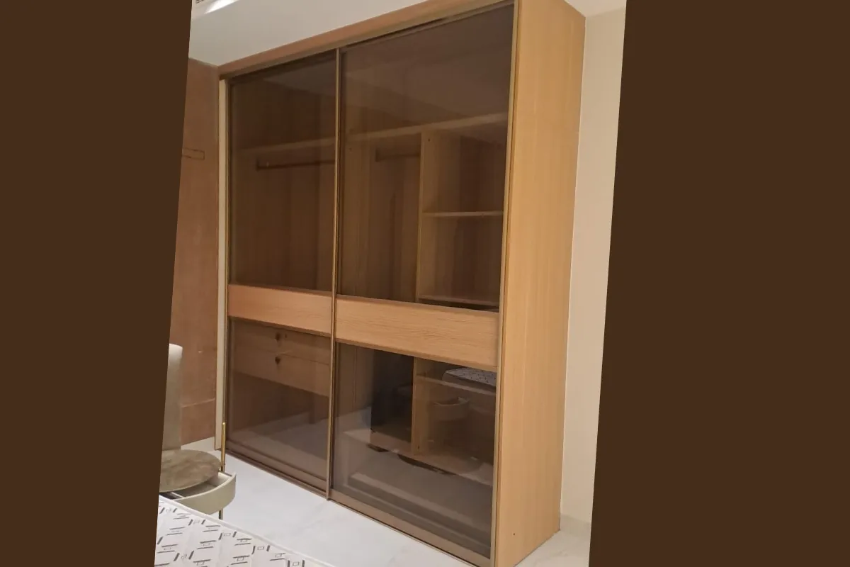 Full-height sliding wardrobe with mirror doors and internal organizers in a master bedroom.