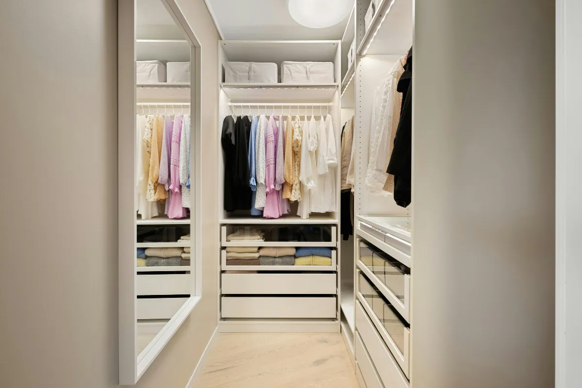 Spacious walk-in closet with glass shelving, shoe racks, drawers, and vanity section